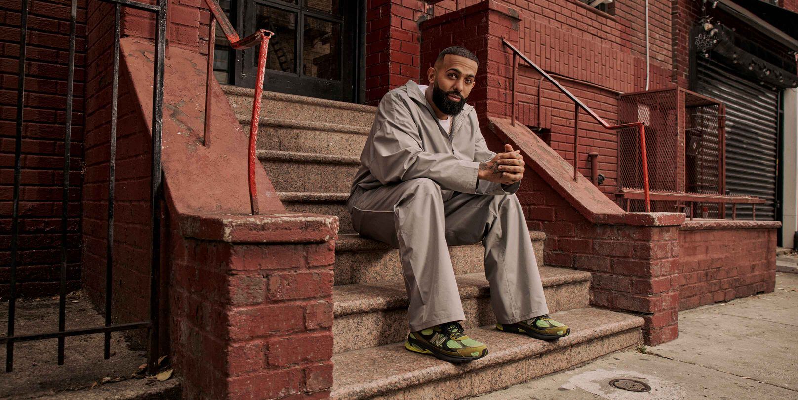 Eladio sitting down by himself on the steps with his hands folded.